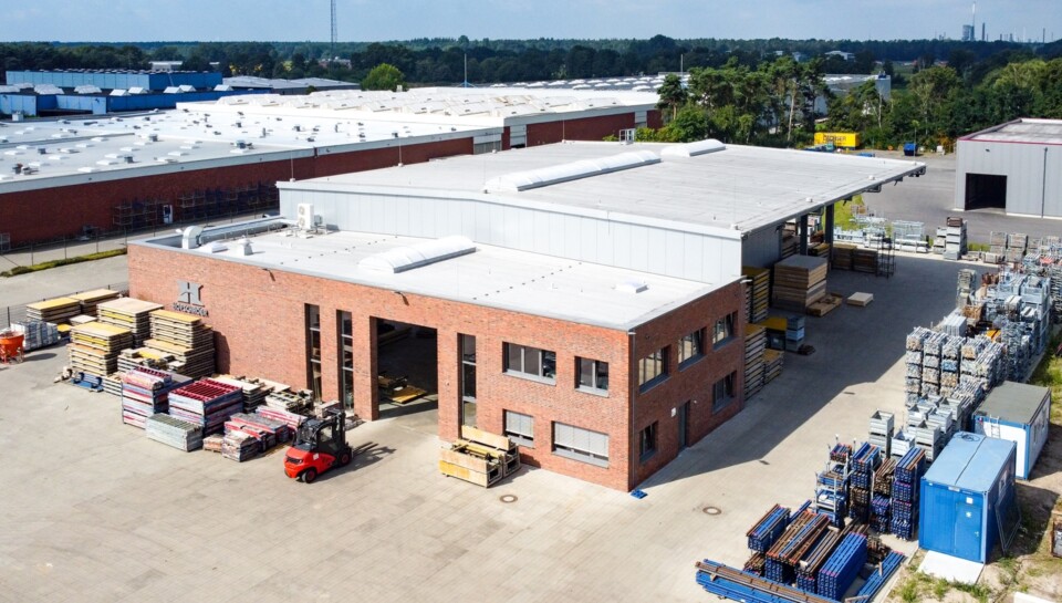 Blick von oben auf das Hofschröer Gebäude, das von Bäumen und Autos umgeben ist, in einer städtebaulichen Umgebung